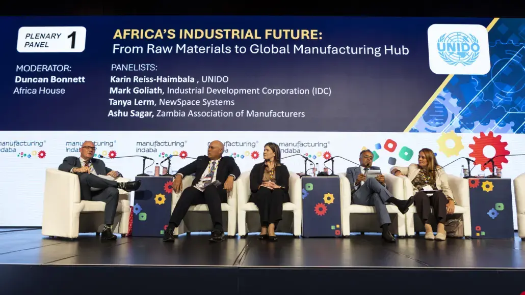 Panel of five speakers seated on stage during a conference panel on Africa's industrial future, with UNIDO banner in background and audience seating offstage.
