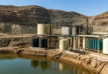 BHP and SiTration Advance Copper Recovery from Mine Water Industrial water treatment setup with pumps, tanks and blue filter columns beside a pond in a rocky quarry setting