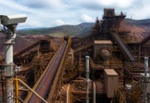 Vale and ABB Push Mining Digital Transformation in Brazil Industrial mining facility with elevated conveyor belts and rust-colored metal structures against a hilly backdrop.