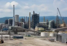 Korea Zinc’s Project Crucible Gains Traction in US Critical Minerals Push Industrial refinery complex with tall distillation towers, interconnected pipes, and a crane in the background; foreground shows a construction area with equipment.