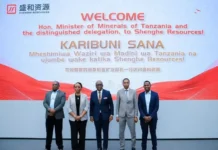Shenghe Mineral Processing Plant Takes Shape in Tanzania Group of five professionals in business attire posing in front of a large welcome banner at a corporate event.