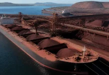 HMM Signs $3.5 Billion Vale Shipping Contract for 25 Years A bulk carrier at a coal terminal with large brown coal piles and conveyor belts nearby.